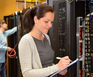 Woman IT engineer in server room checking network